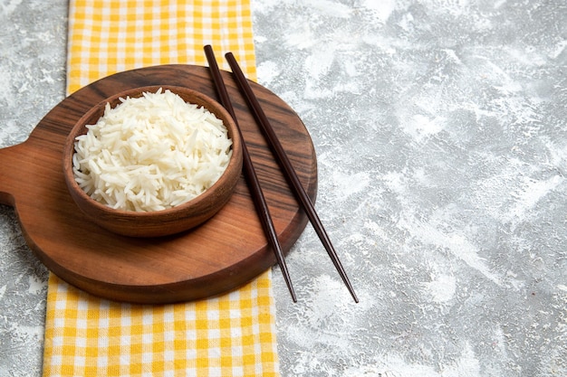 Vista frontal delicioso arroz cocido dentro de la placa marrón en el espacio en blanco