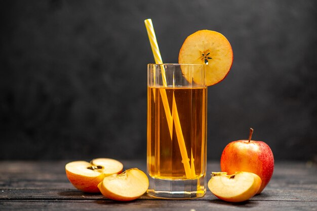 Vista frontal del delicioso jugo natural fresco en dos vasos con limones de manzana roja sobre fondo negro