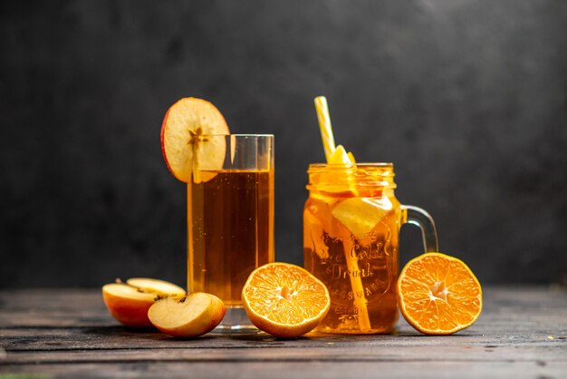 Vista frontal del delicioso jugo natural fresco en dos vasos mano poniendo limas de frutas con tubo sobre fondo negro