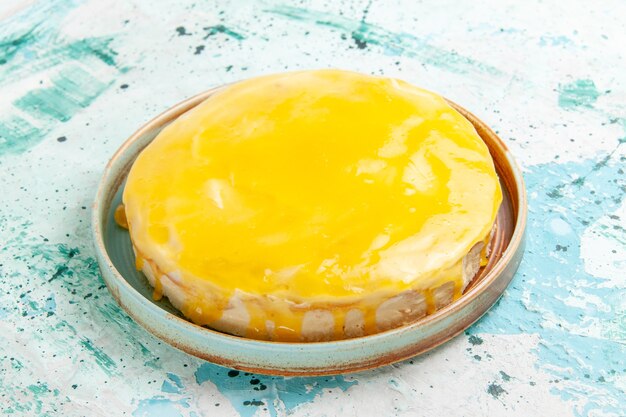 Vista frontal delicioso pastel con almíbar amarillo sobre la superficie azul