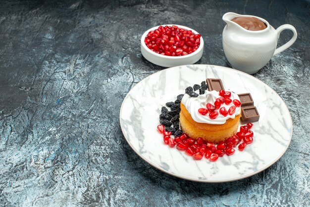 Vista frontal delicioso pastel cremoso con chocolate y pasas sobre fondo claro-oscuro galletas de azúcar postre dulce