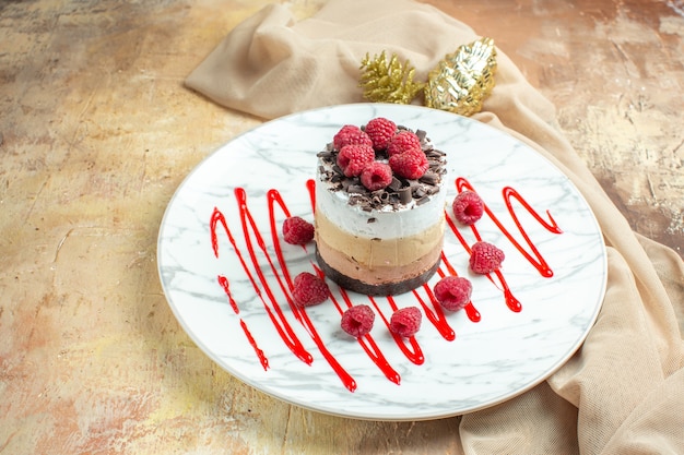 Vista frontal delicioso pastel cremoso dentro de la placa con frambuesas frescas en mesa marrón