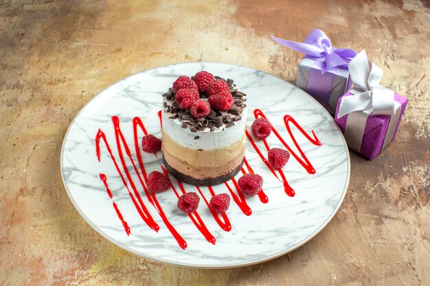 Vista frontal delicioso pastel cremoso dentro de la placa con frambuesas en mesa marrón