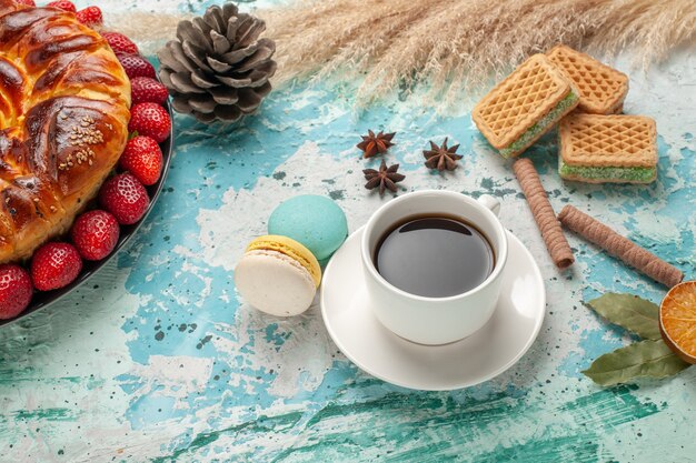 Vista frontal delicioso pastel dulce con fresas rojas frescas waffles y taza de té sobre superficie azul