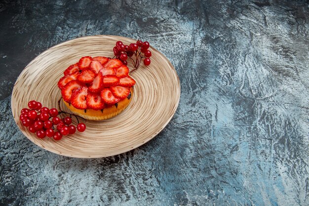 Vista frontal del delicioso pastel de fresa con frutos rojos sobre superficie oscura