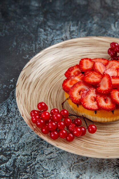 Vista frontal del delicioso pastel de fresa con frutos rojos sobre superficie oscura