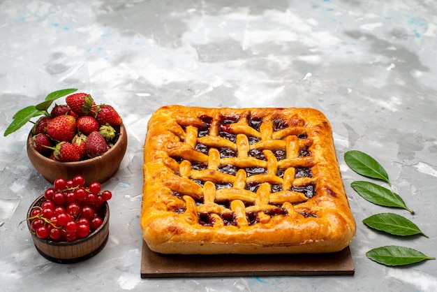 Una vista frontal delicioso pastel de fresa con gelatina de fresa en el interior junto con fresas frescas y arándanos en el pastel de escritorio gris