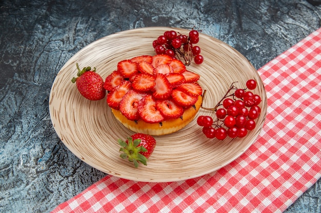Vista frontal del delicioso pastel con fresas frescas sobre superficie gris