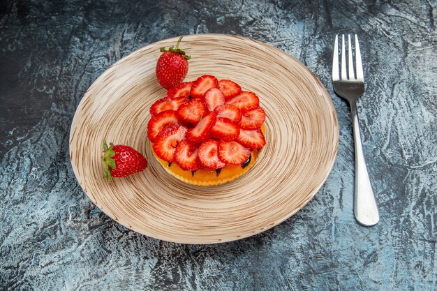 Vista frontal del delicioso pastel con fresas frescas sobre una superficie oscura