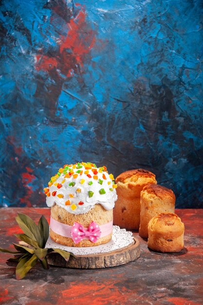 Vista frontal delicioso pastel de pascua con crema blanca y frutas secas sobre fondo oscuro pastel colorido de primavera hornear concepto adornado dulce