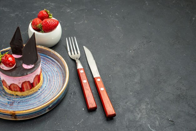 Vista frontal delicioso pastel de queso con fresa y chocolate en plato tazón con tenedor de fresas