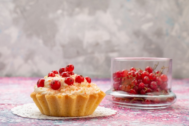 Vista frontal delicioso pastel redondo con crema y arándanos rojos frescos sobre la superficie ligera de azúcar