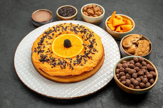 Vista frontal delicioso pastel con rodajas de naranja sobre fondo oscuro pastel de tarta de postre de fruta de galleta de té