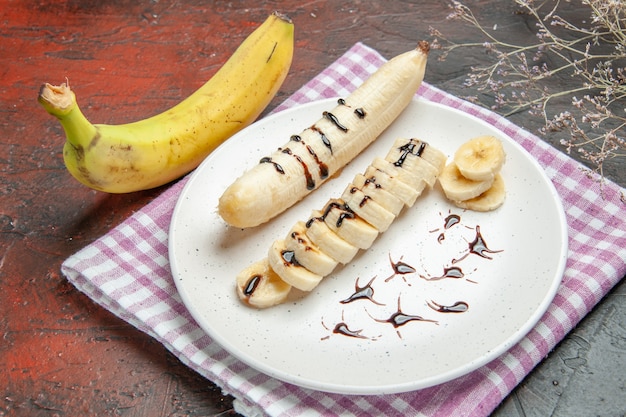 Foto gratuita vista frontal delicioso plátano con trozos en rodajas dentro de la placa sobre fondo oscuro foto de árbol frutal sabor dulce