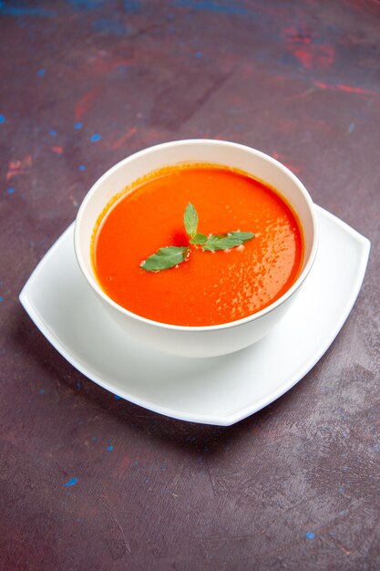 Vista frontal delicioso plato sabroso de sopa de tomate con una sola hoja dentro de la placa en un espacio oscuro