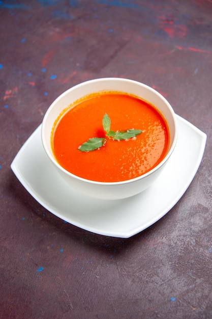 Vista frontal delicioso plato sabroso de sopa de tomate con una sola hoja dentro de la placa en un espacio oscuro