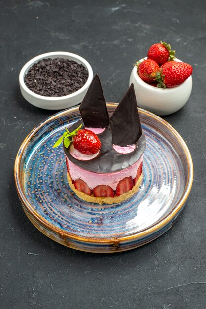Vista frontal delicioso tarta de queso con fresa y chocolate en tazones de fuente con chocolate de fresas en la oscuridad