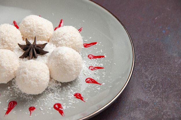 Foto gratuita vista frontal de deliciosos caramelos de coco con glaseados rojos en el espacio oscuro