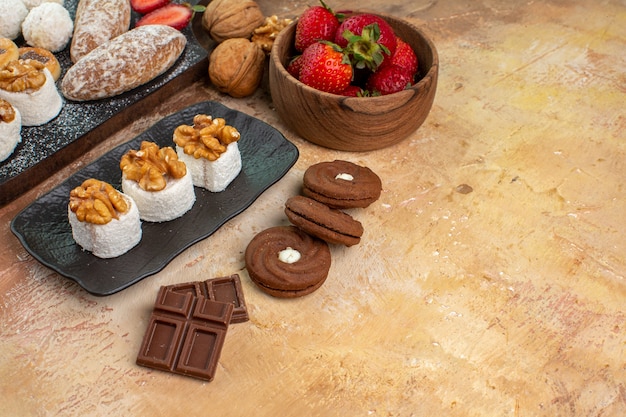 Vista frontal deliciosos dulces con frutas dulces y galletas en un escritorio de madera