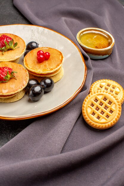 Vista frontal deliciosos panqueques con aceitunas y frutas sobre una superficie oscura pastel de frutas dulces