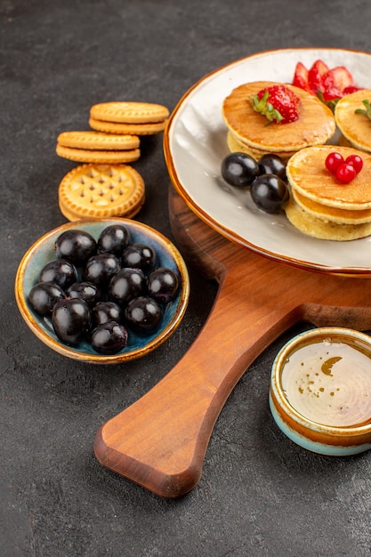 Vista frontal deliciosos panqueques con aceitunas y frutas en la superficie oscura pastel dulce de frutas