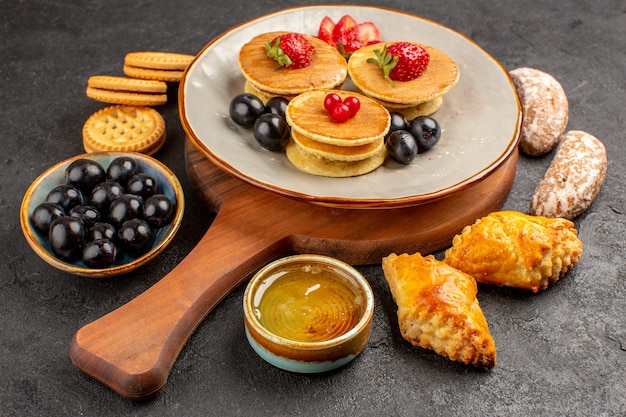 Vista frontal deliciosos panqueques con aceitunas y tortas en pastel dulce de frutas de superficie oscura