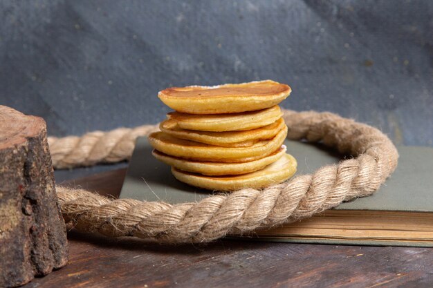 Vista frontal de deliciosos panqueques con cuerdas en la superficie gris