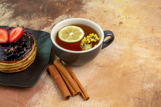 Vista frontal deliciosos panqueques dulces con taza de té en la mesa de luz pastel dulce postre leche