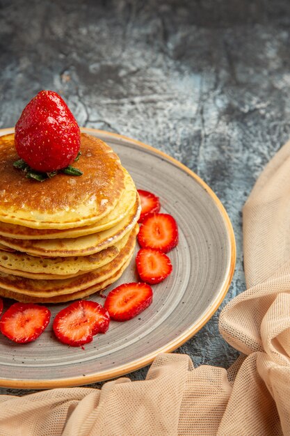 Vista frontal deliciosos panqueques con fresas frescas sobre una superficie ligera pastel frutas dulces