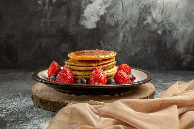 Vista frontal deliciosos panqueques con frutas y miel en la superficie ligera de leche de frutas dulces