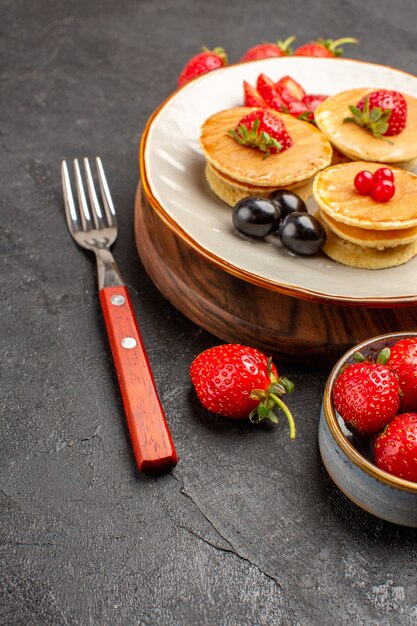 Vista frontal deliciosos panqueques con frutas en la superficie oscura pastel pastel frutas dulces