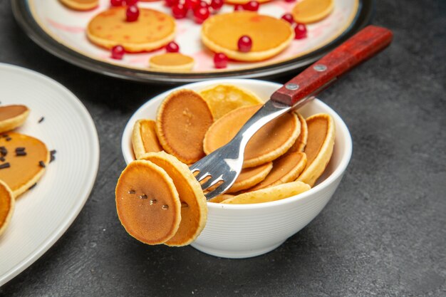 Vista frontal deliciosos panqueques con frutos rojos en la oscuridad