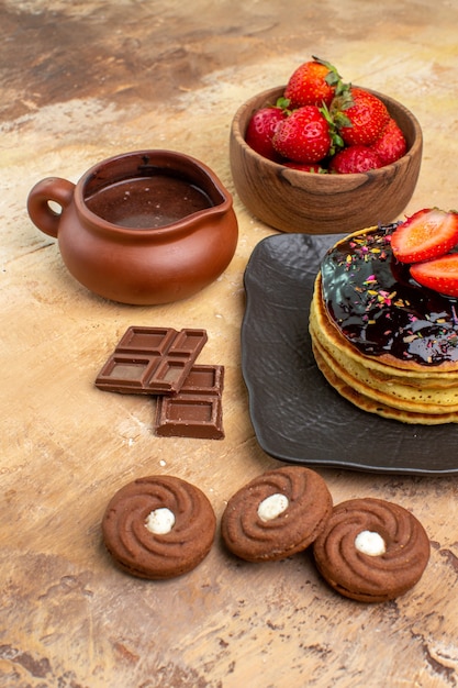 Vista frontal deliciosos panqueques con galletas y frutas en un escritorio de madera pastel de postre pastel dulce