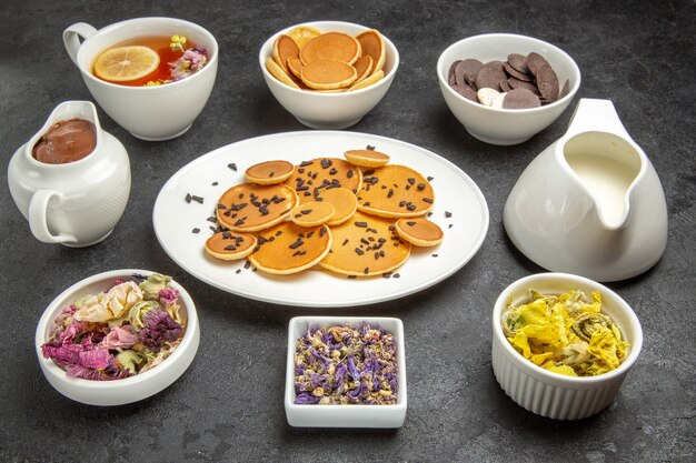 Vista frontal deliciosos panqueques con galletas y té en la oscuridad