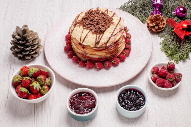 Vista frontal deliciosos panqueques con gelatina y fresas en el escritorio blanco pastel pastel galleta de frutas baya dulce