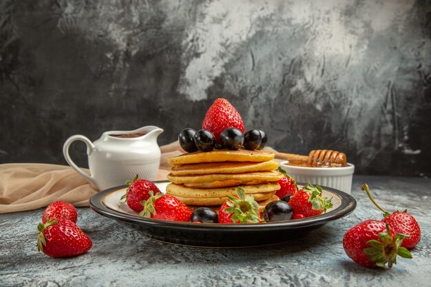 Vista frontal deliciosos panqueques con miel y frutas en frutas de pastel dulce de superficie ligera