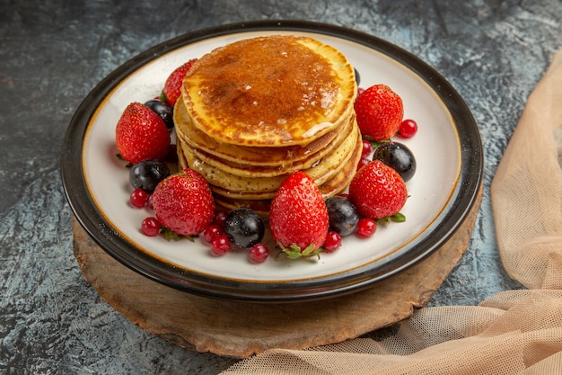 Vista frontal deliciosos panqueques con miel y frutas en leche de fruta dulce de superficie ligera