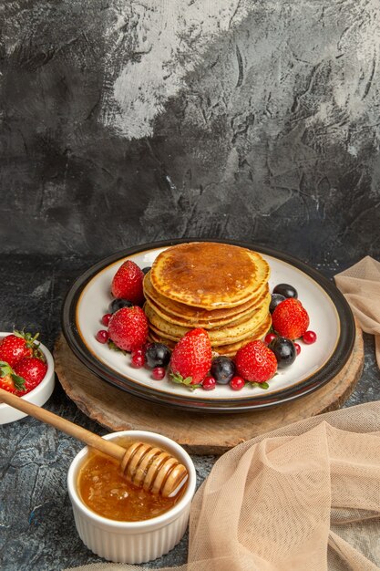 Vista frontal deliciosos panqueques con miel y frutas en piso de luz fruta dulce de leche