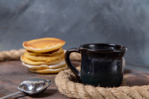 Vista frontal deliciosos panqueques con taza de leche en el desayuno de comida de azúcar dulce de fondo gris