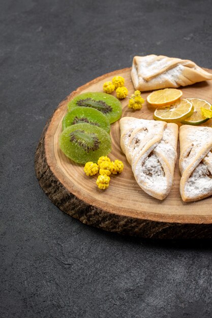 Vista frontal deliciosos pasteles con anillos de piña secos y kiwis en espacio gris