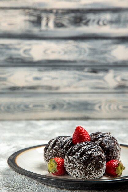 Foto gratuita vista frontal deliciosos pasteles de chocolate con fresas rojas en la pared de color blanco claro galleta de azúcar de chocolate pastel dulce hornear galletas