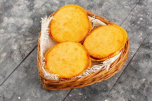 vista frontal deliciosos pasteles cocidos redondos dentro de la canasta en el piso gris