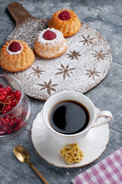 Vista frontal deliciosos pasteles d con taza de café y arándanos rojos frescos en el escritorio gris fruta dulce