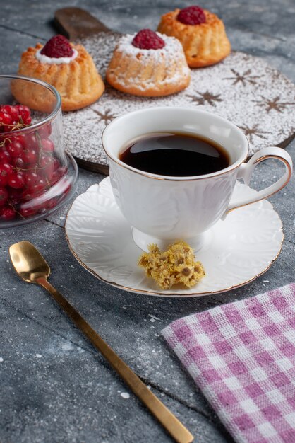 Vista frontal deliciosos pasteles d con taza de café y arándanos rojos frescos en el escritorio gris galleta fruta dulce
