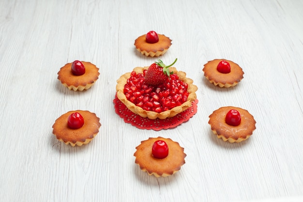 Vista frontal deliciosos pasteles con frutas en un dulce de galletas de pastel de escritorio blanco