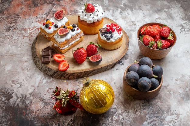 Vista frontal deliciosos pasteles con frutas frescas sobre fondo claro pastel de navidad postre color de galleta