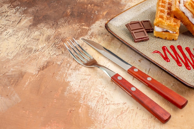 Vista frontal deliciosos pasteles de gofres con barras de chocolate en el fondo marrón