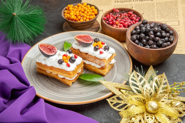 Vista frontal deliciosos pasteles de gofres con frutas frescas sobre fondo oscuro