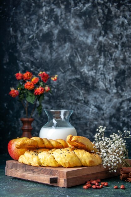Vista frontal deliciosos pasteles con harina y leche en una pared oscura pastel pastel hotcake bollo dulce masa de postre azúcar