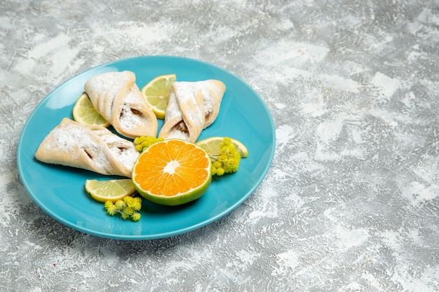 Vista frontal de deliciosos pasteles de masa con rodajas de limón en la pared blanca pastelería azúcar hornear masa pastel dulce pastel